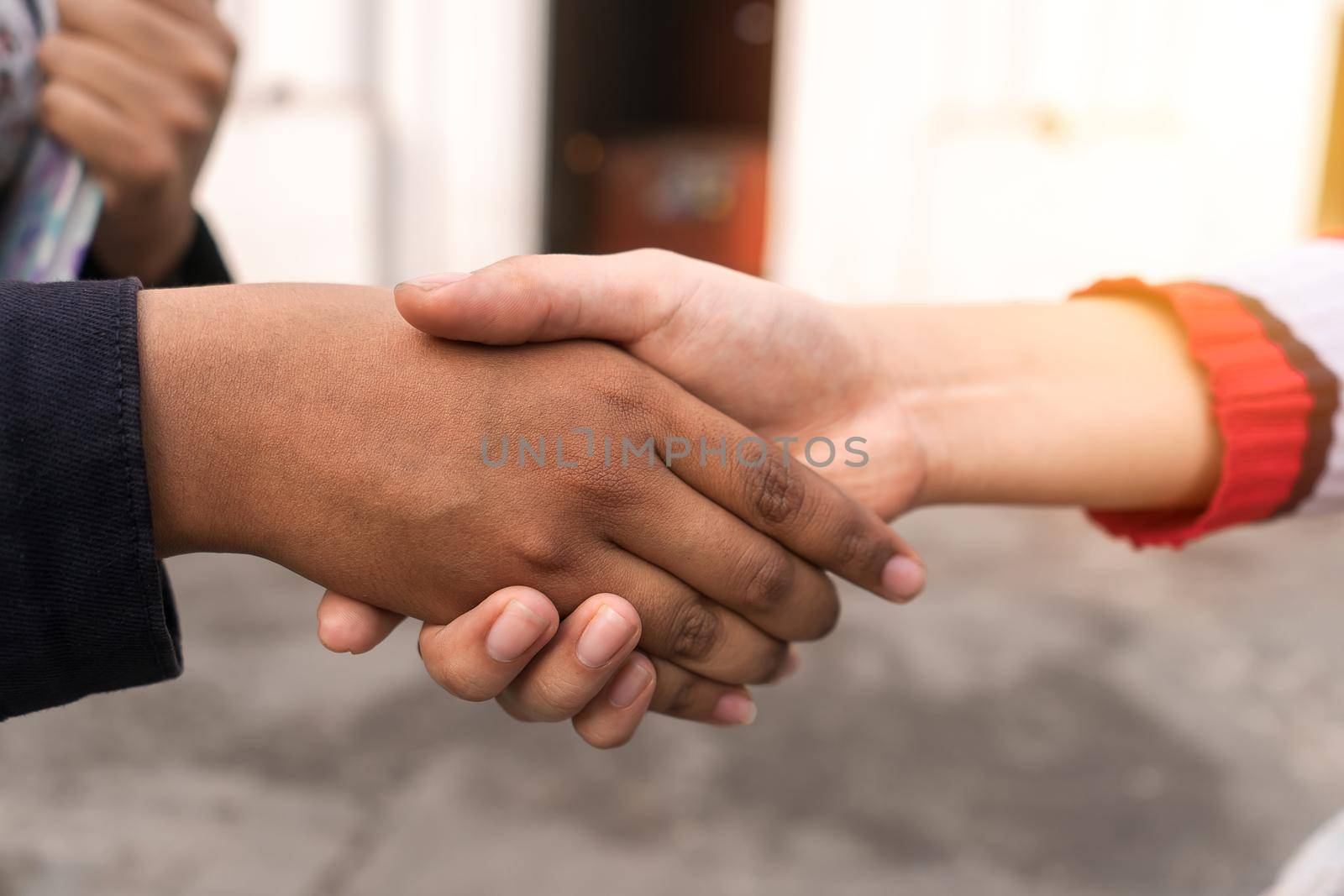 Closeup to the hands of two young Latin women, one mestiza and one Latin, shaking hands for a deal and working as a team during their academic activities.