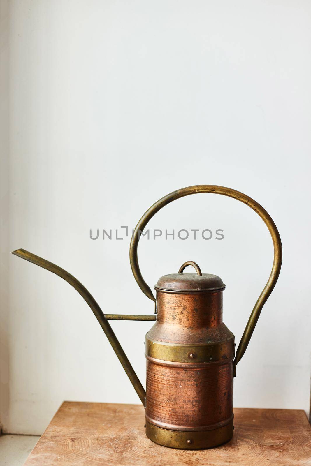 Vintage copper watering can on a wooden stand