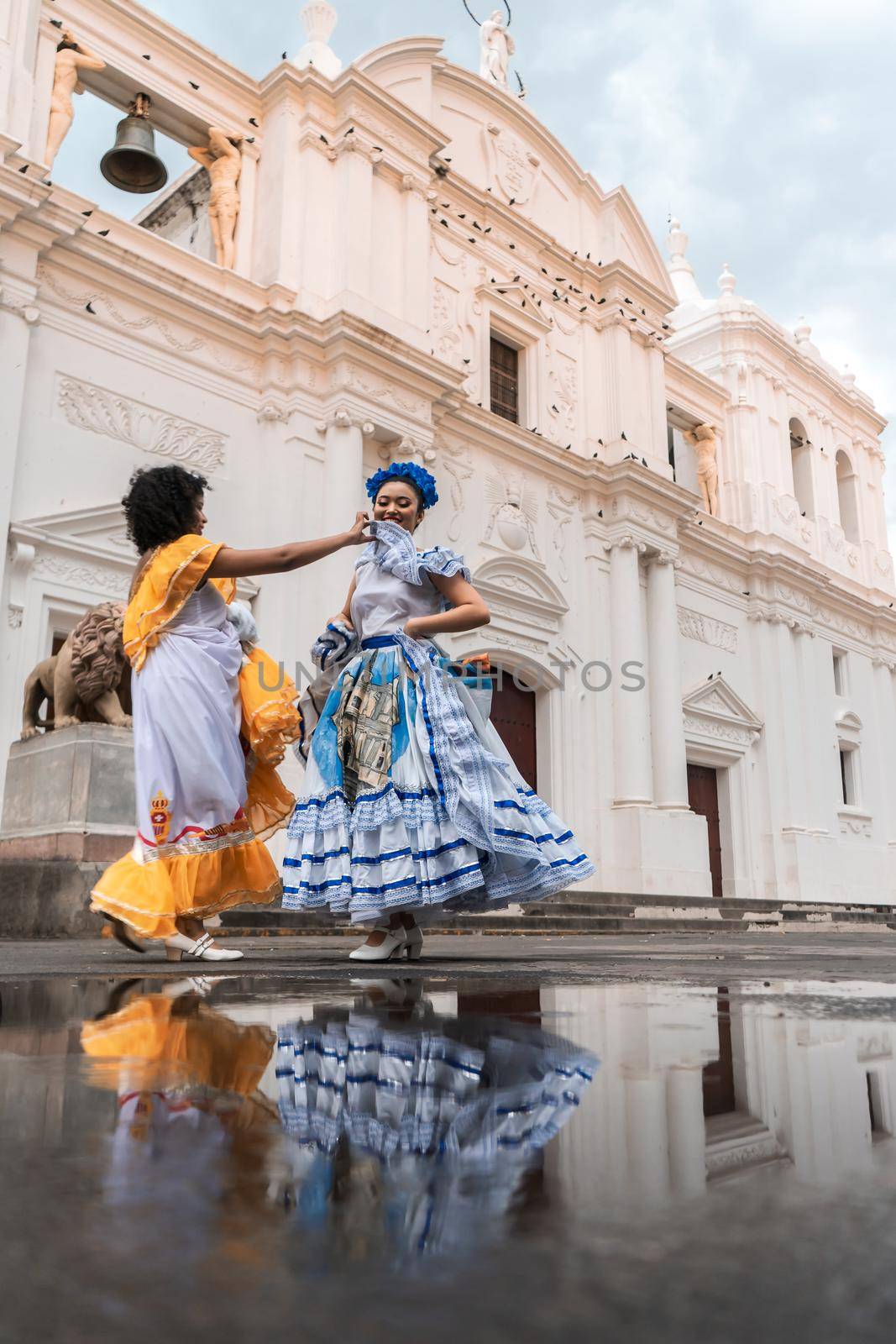 Traditional Nicaraguan folklore dancers fixing their dresses in front of the cathedral church in Leon Nicaragua.