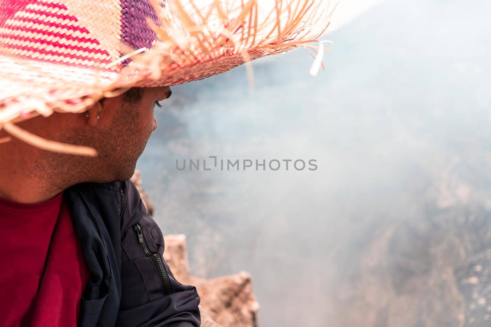 Unrecognizable man with a colorful hat in amazement and looking towards the crater of the Masaya volcano in Nicaragua. Photo with copy space.