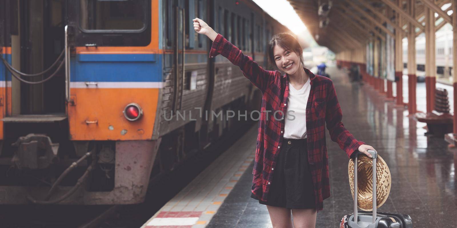 Happy Young traveler woman looking for friend planning trip at train station. Summer and travel lifestyle concept. by itchaznong