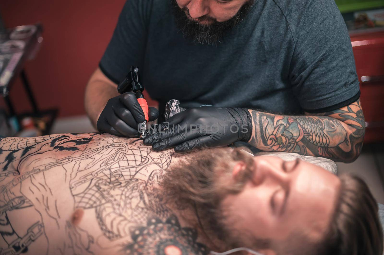Master tattooist makes a tattoo on the skin in a workshop studio by Proff
