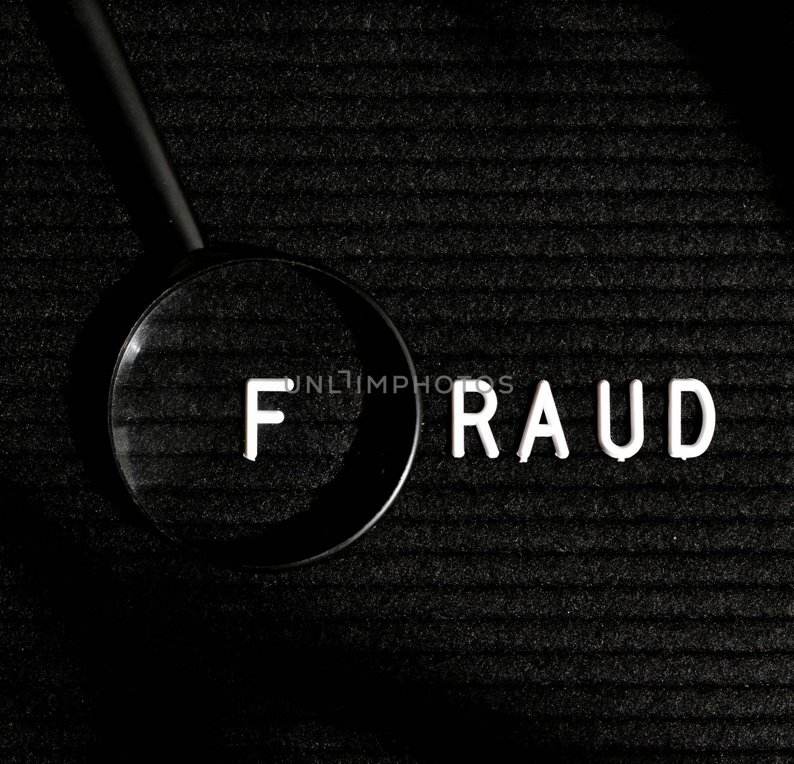 fraud word with letter magnifying glass top view by Zahard