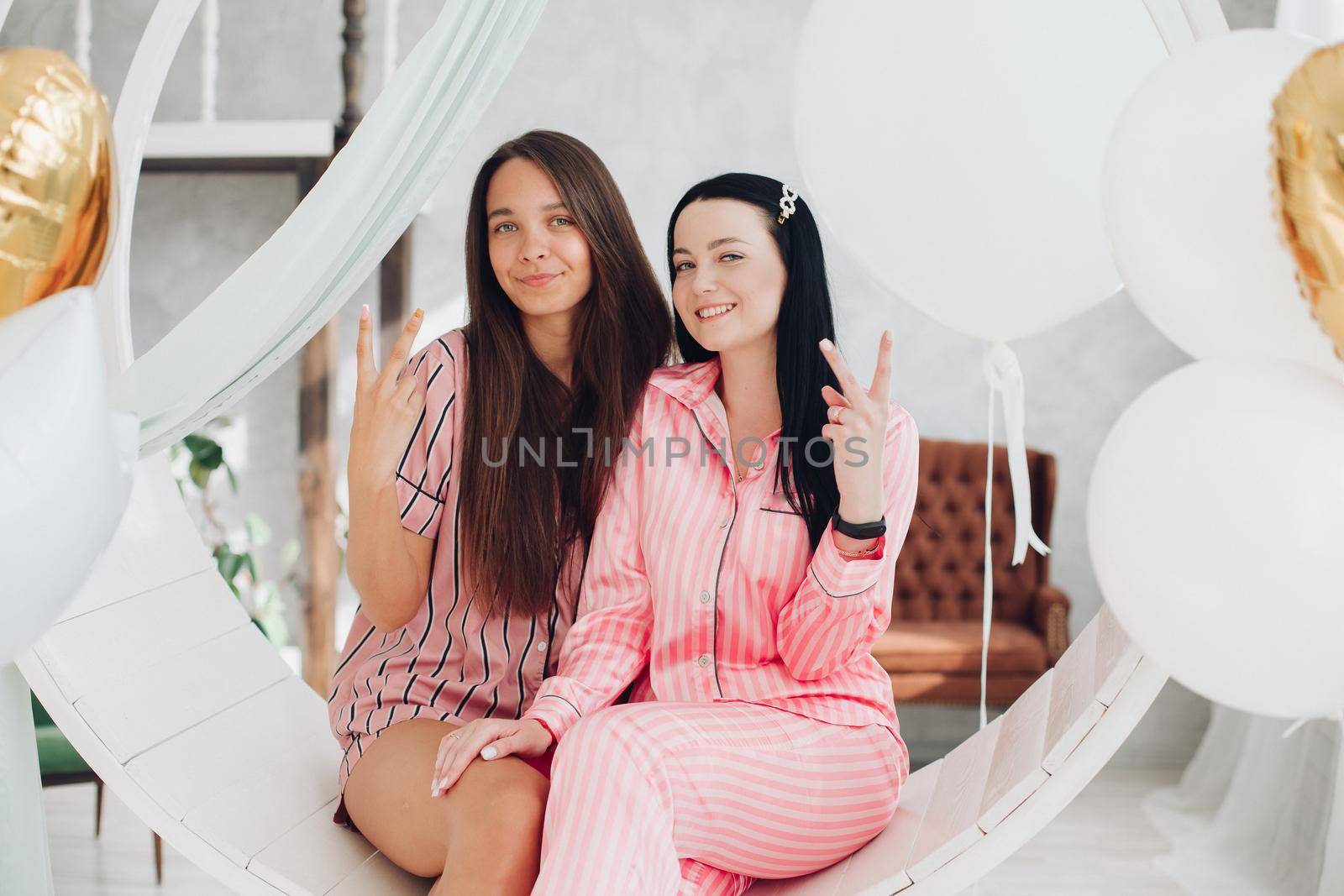 Two pretty girls on beautiful swing indoors. by StudioLucky