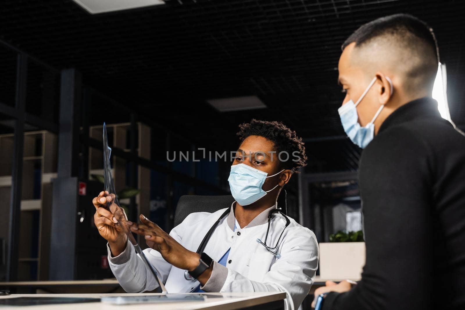 African doctor show x-ray asian patient. Black surgeon analyzing x ray and diagnosis patient in medical clinic