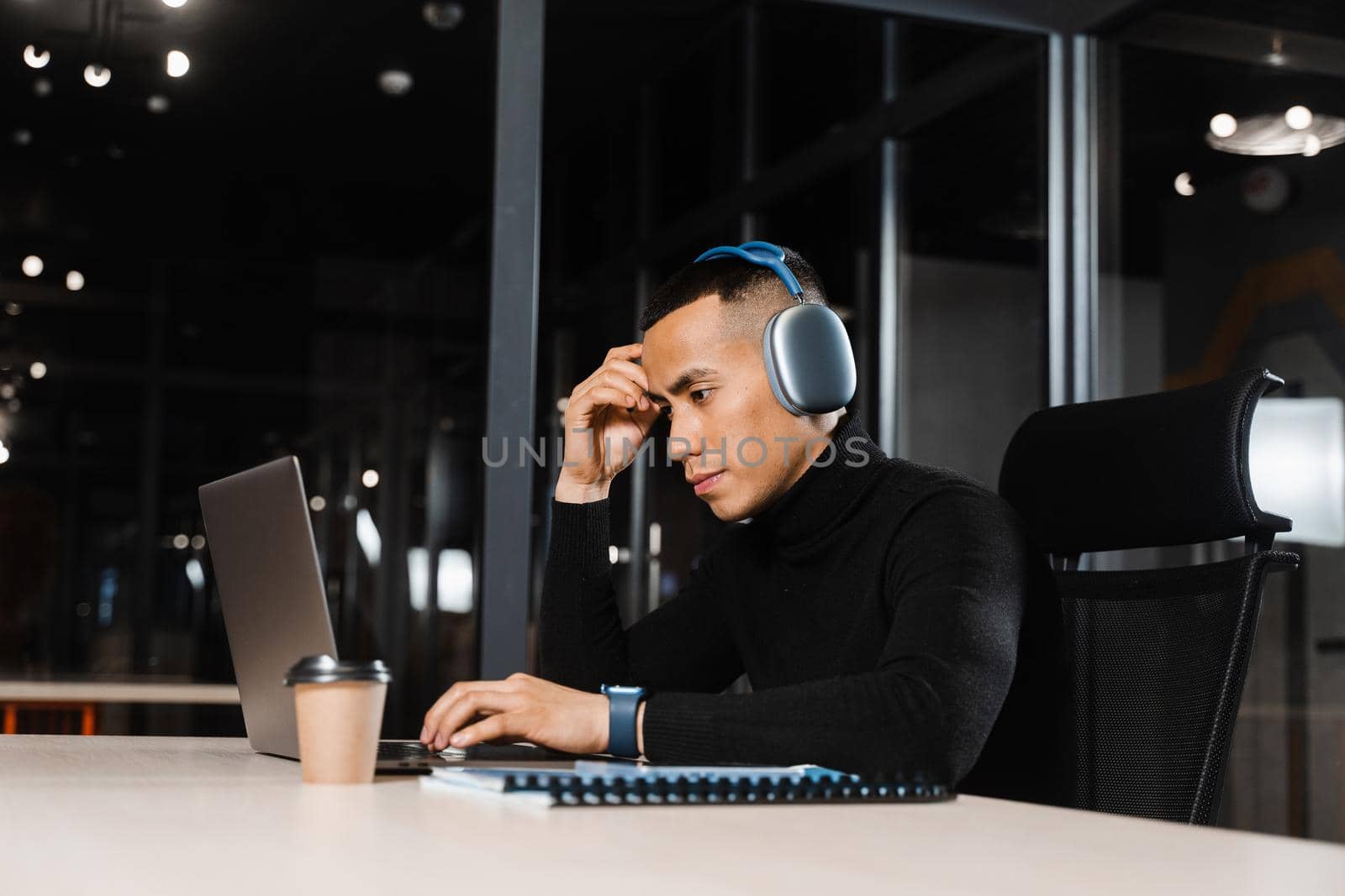 Asian man holding his head and thinking about working online at a laptop. Handsome man worries about remote work