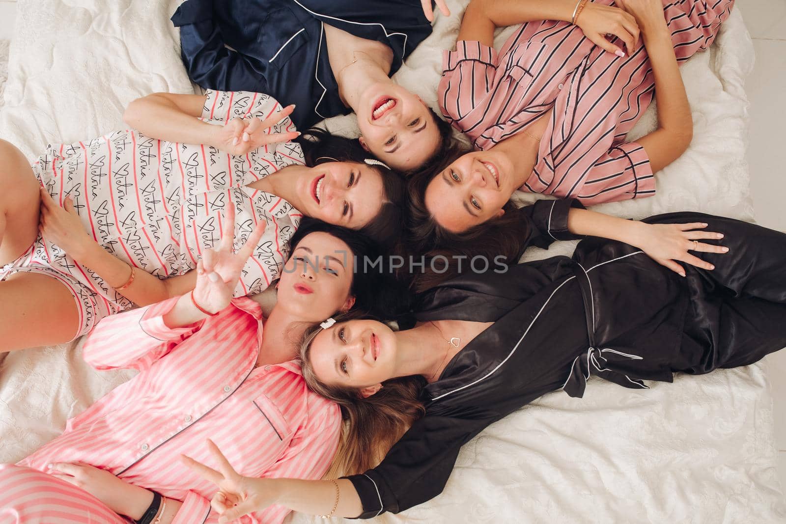 Top view relaxing young girl friends lying on bed having fun posing together by StudioLucky