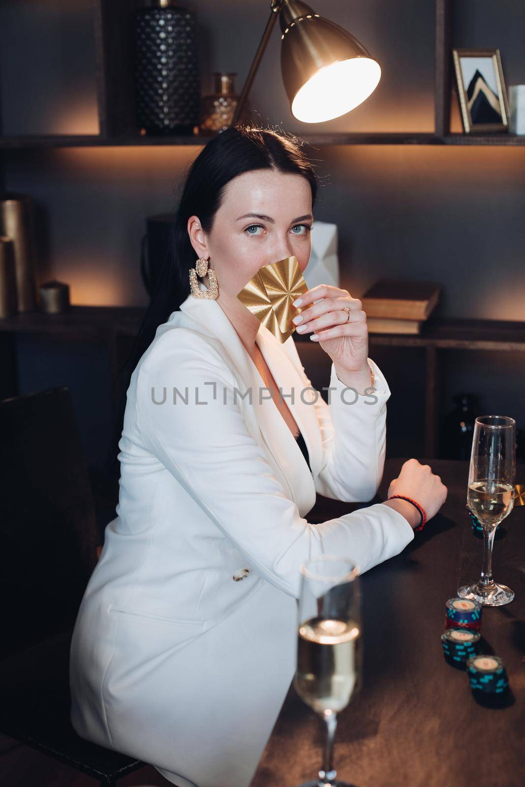 Waist up of beautiful young lady with red lips holding two cards and glass of champagne. Passion and victory concept