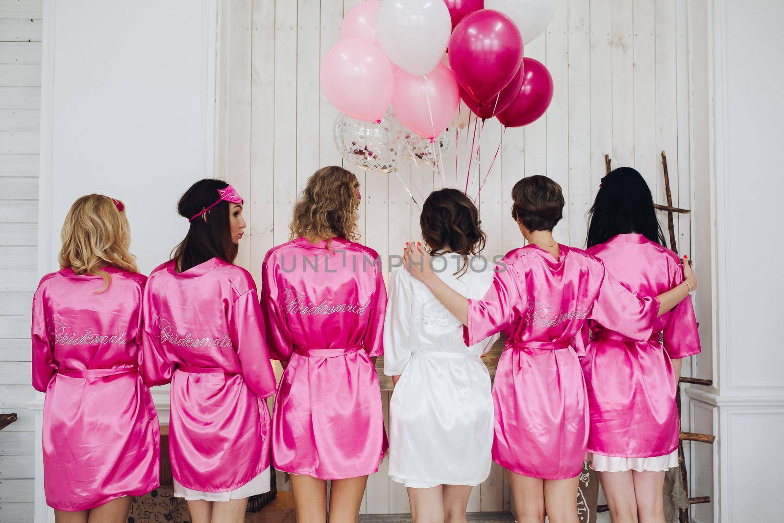 Bridesmaids in pink silk robes with the word 'bridesmaid' on bac by StudioLucky