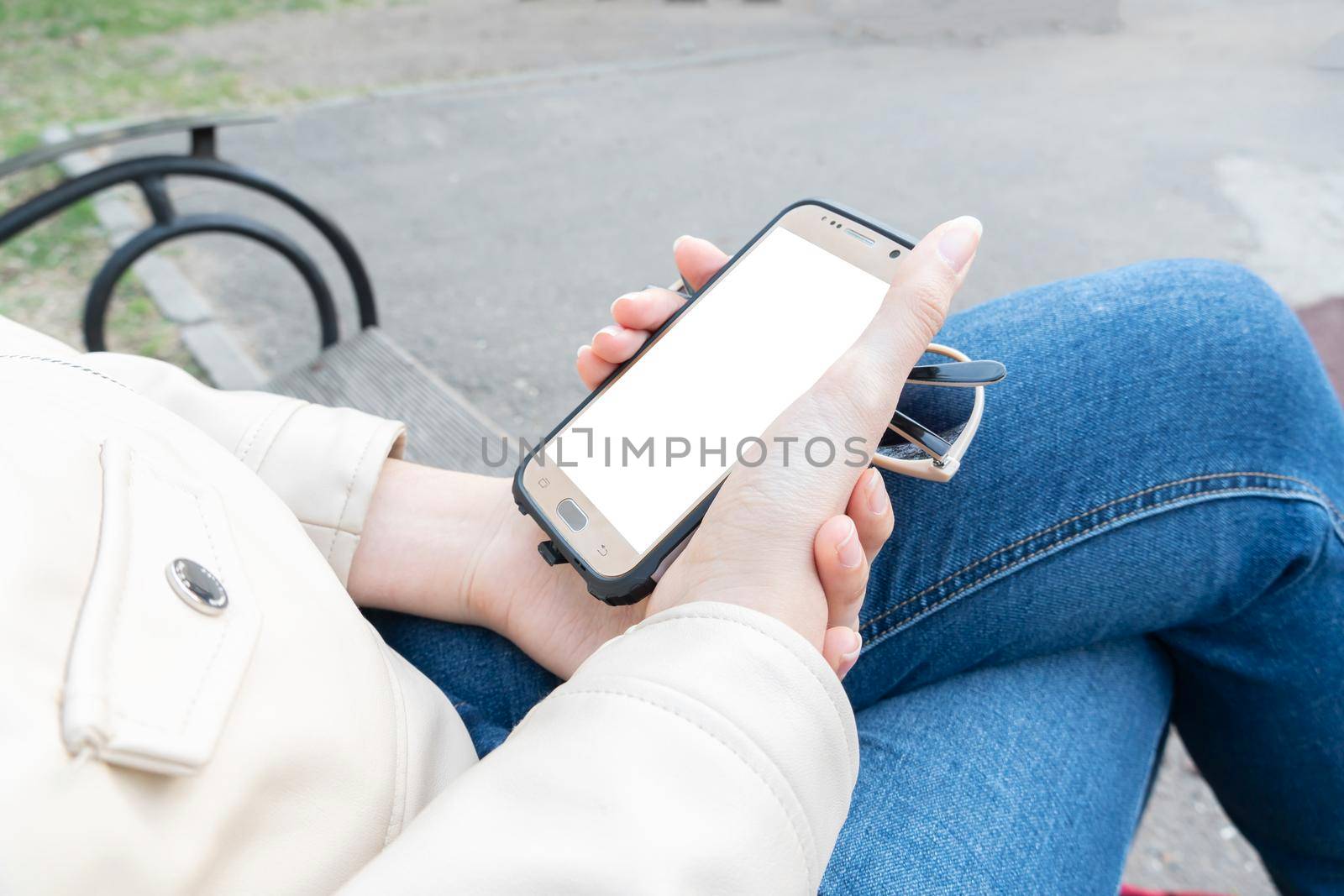 The girl holds in her hand a smartphone with a white screen for your layout or advertising on the phone display.A means of communication,communication and the Internet.Banner,billboard,poster,playbill