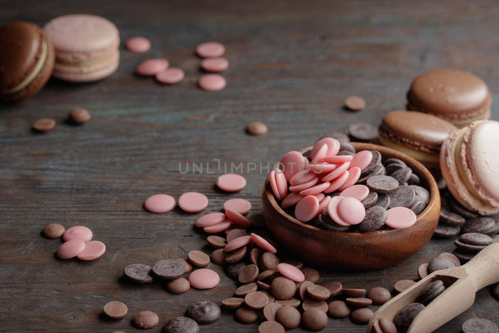 Macaroons with a chocolate drops on a wooden background