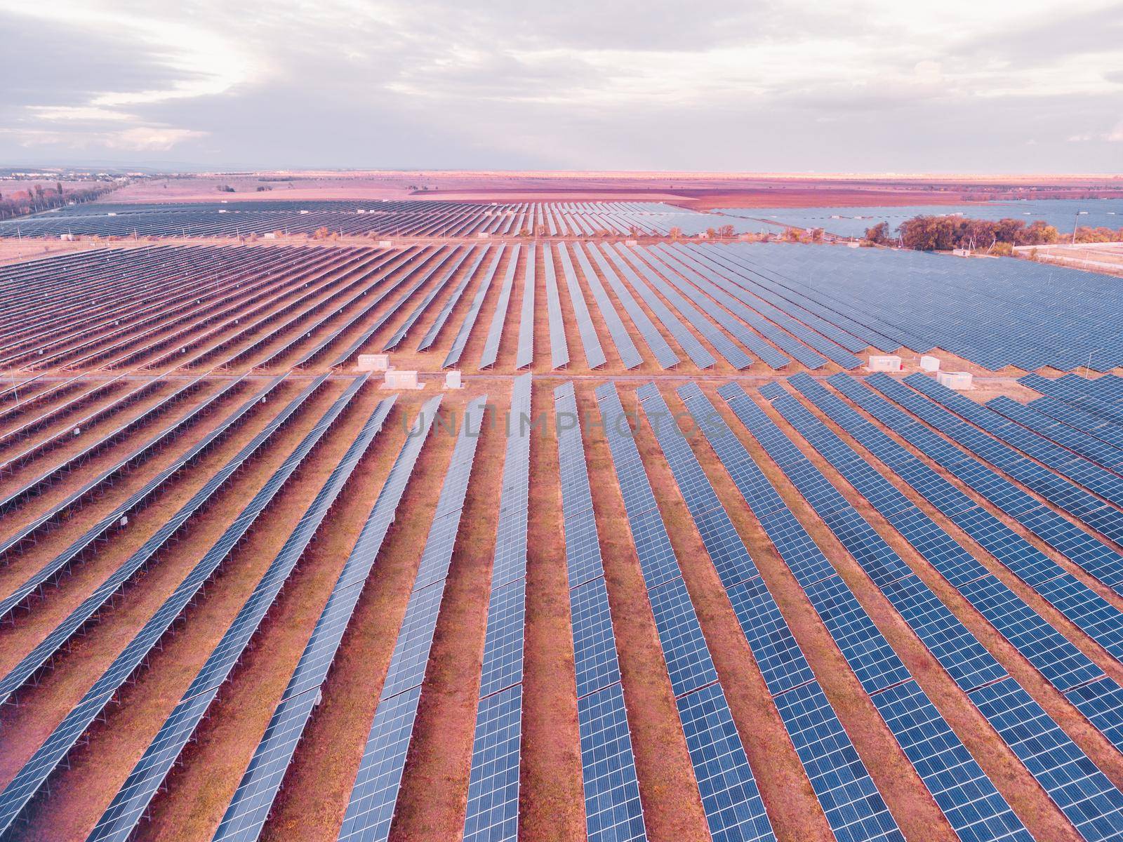 Aerial top view of a solar panels power plant. Photovoltaic solar panels at sunrise and sunset in countryside from above. Modern technology, climate care, earth saving, renewable energy concept