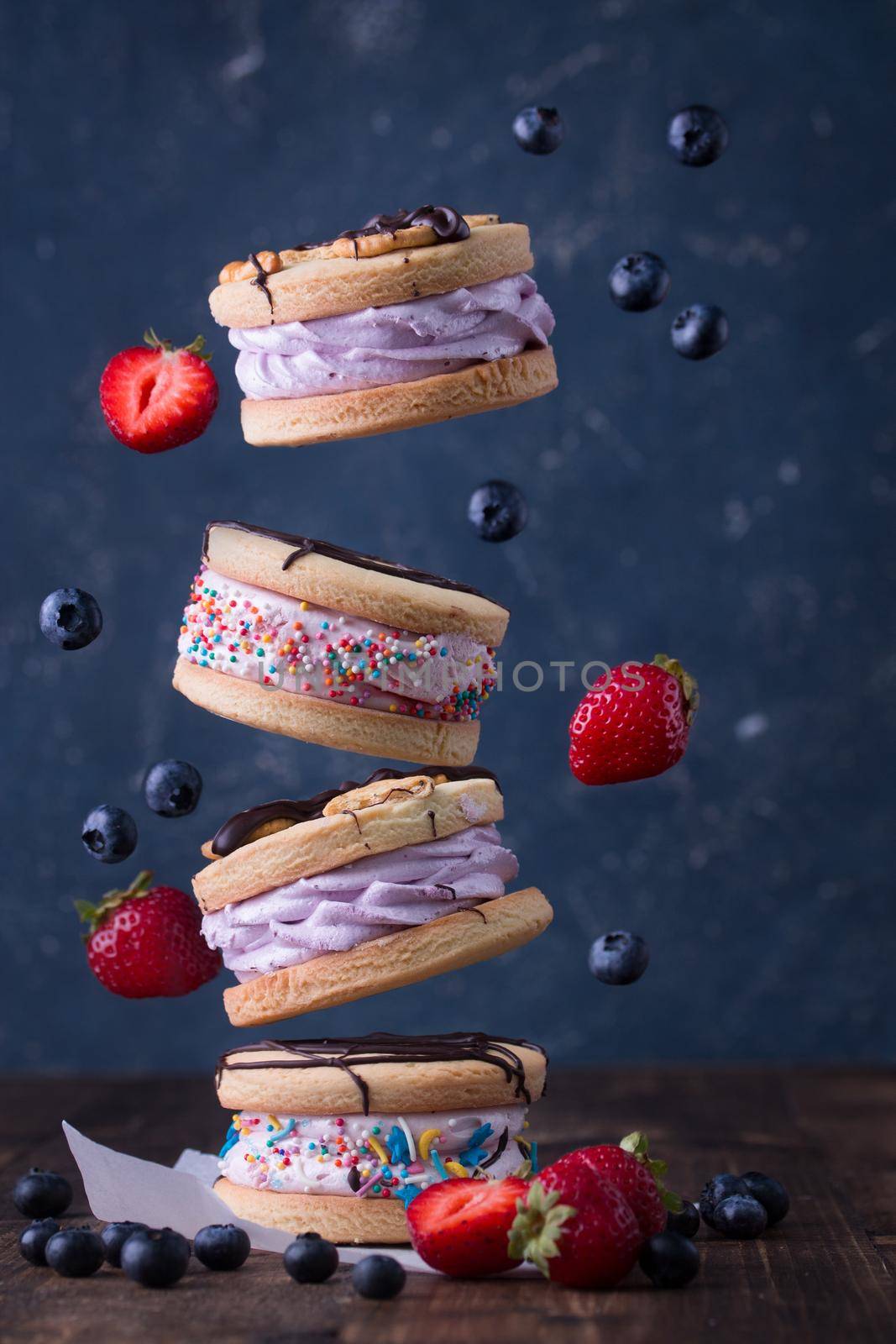 Sweet cookie sandwiches with berries on a blue background