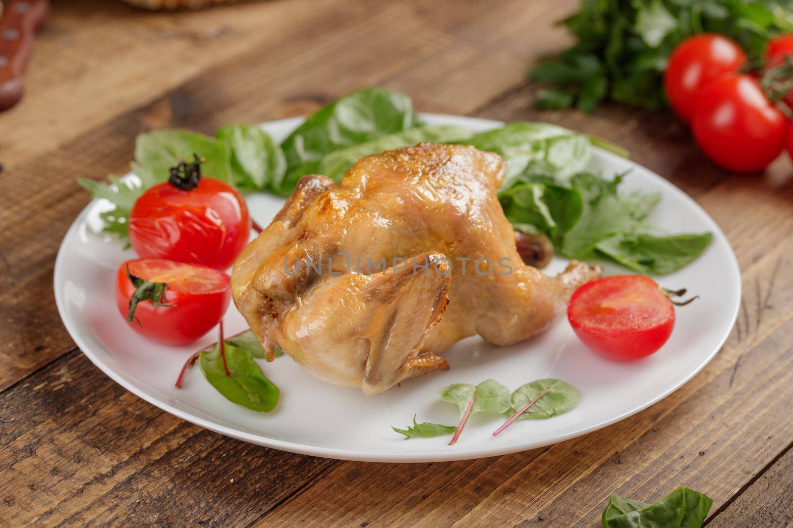 Whole fried chicken with grilled tomatoes on a wooden table
