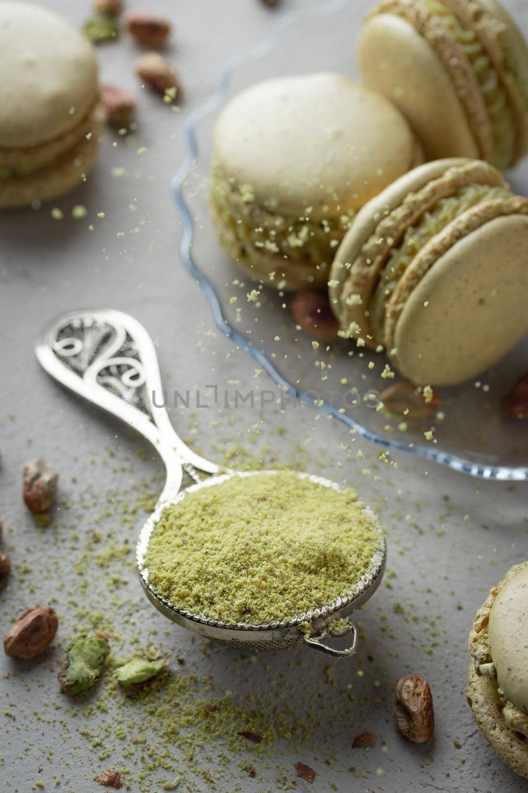Pistachio flour and green macaroons on a gray background