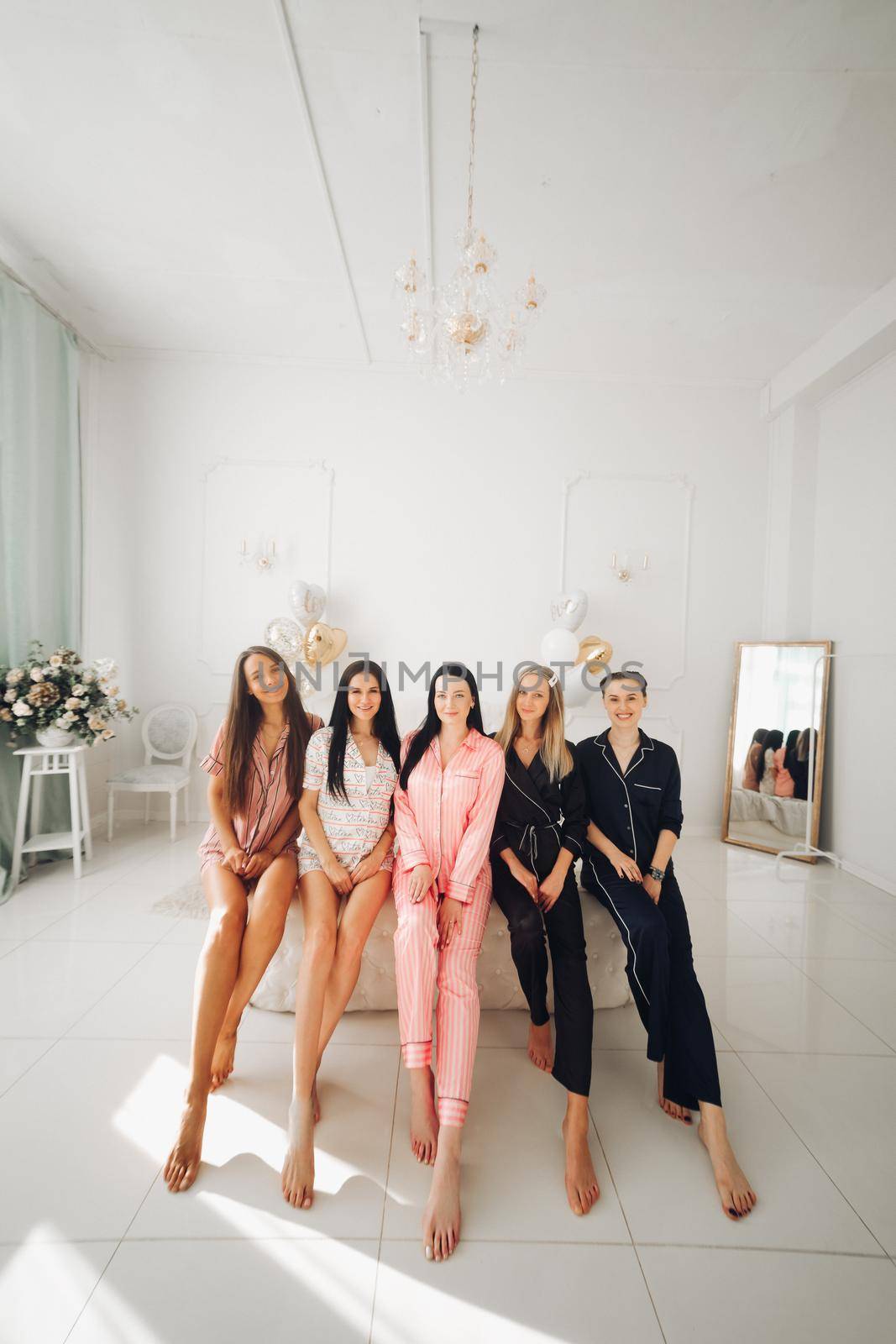 Smiling beautiful women in sleepwear spending time together during home party. Birthday party concept
