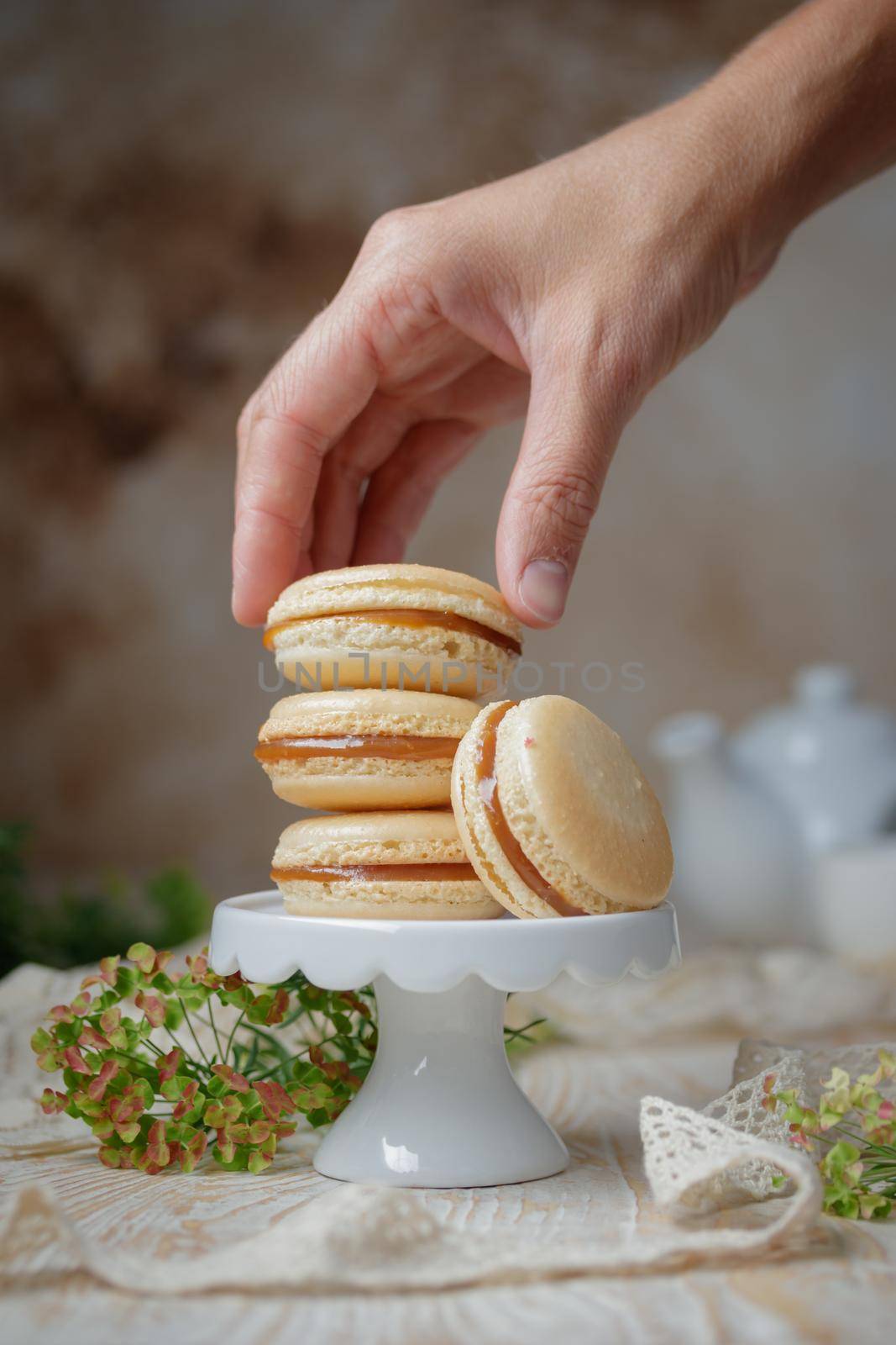 Stack of caramel macaroons on a stand on a wooden background