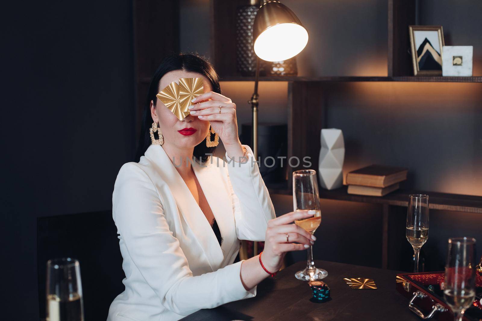 Pretty woman with drink and cards playing poker by StudioLucky