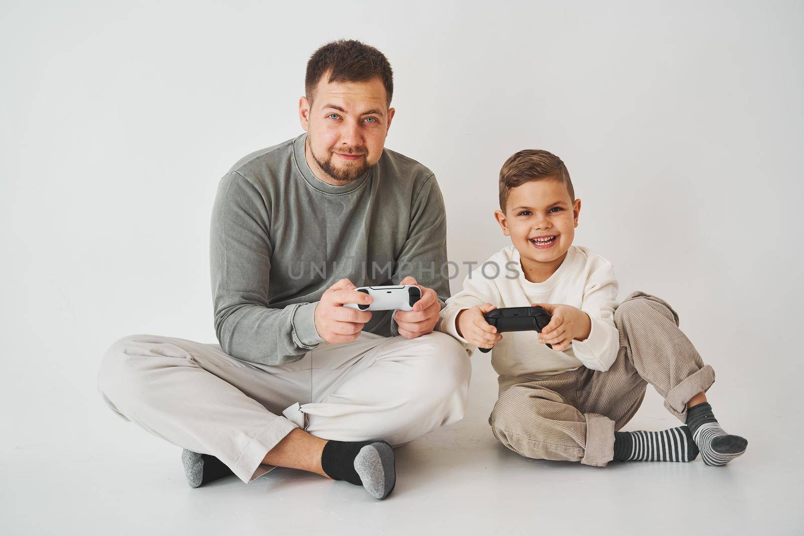 Paternity. Father and son play gamepad console game laugh and have fun together. Gamers play computer games