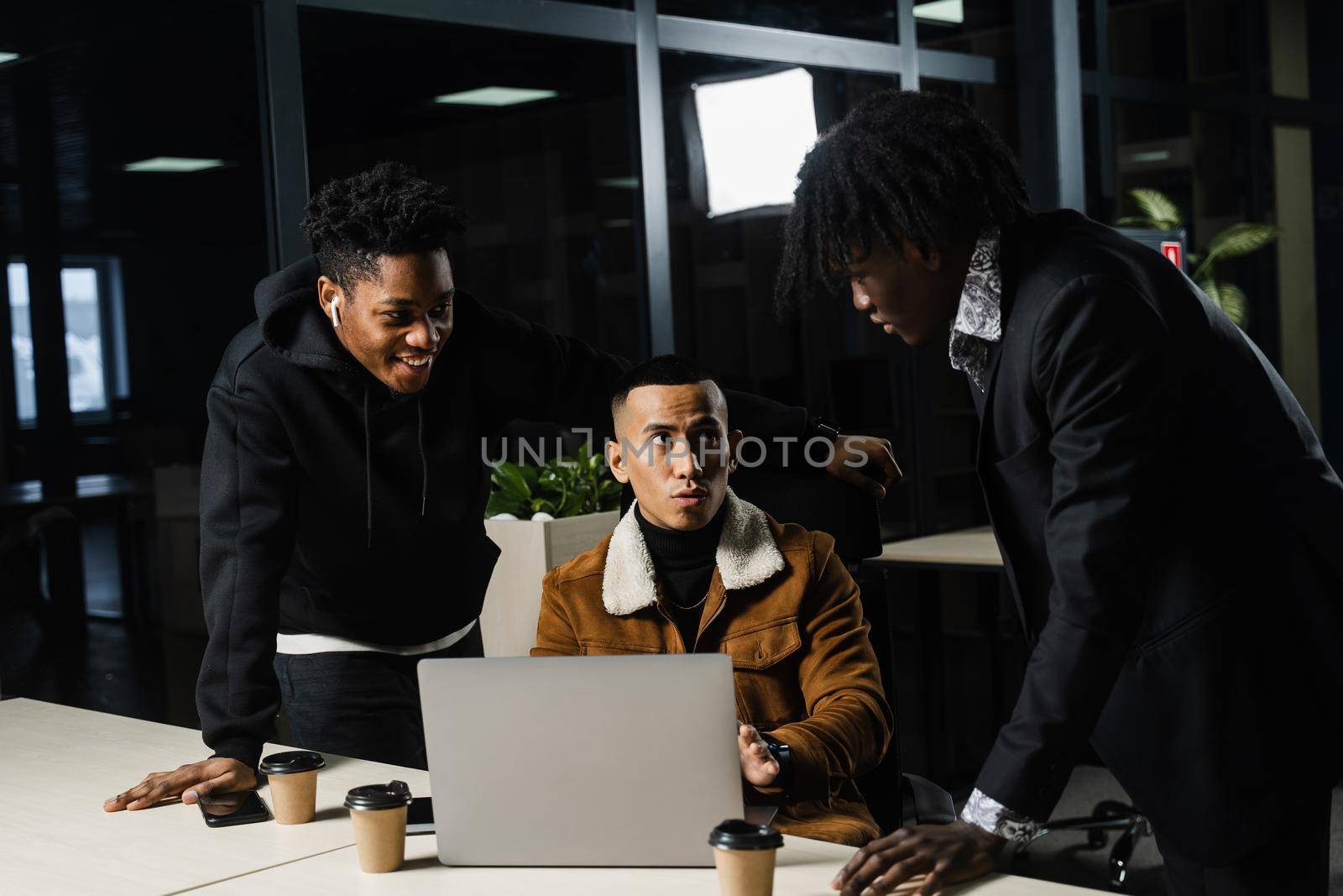 Multiethnic teambuilding and discussing online work project. Black and asian colleagues working on laptop together