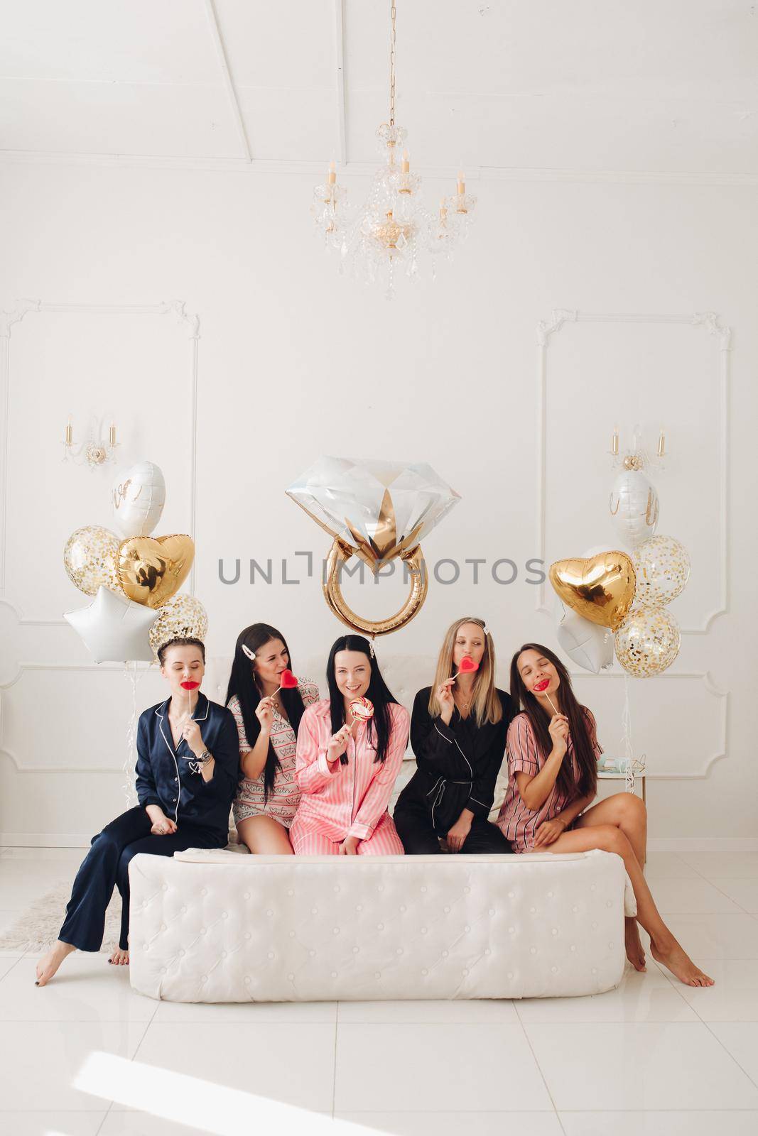 Smiling beautiful women in sleepwear spending time together during home party. Birthday party concept