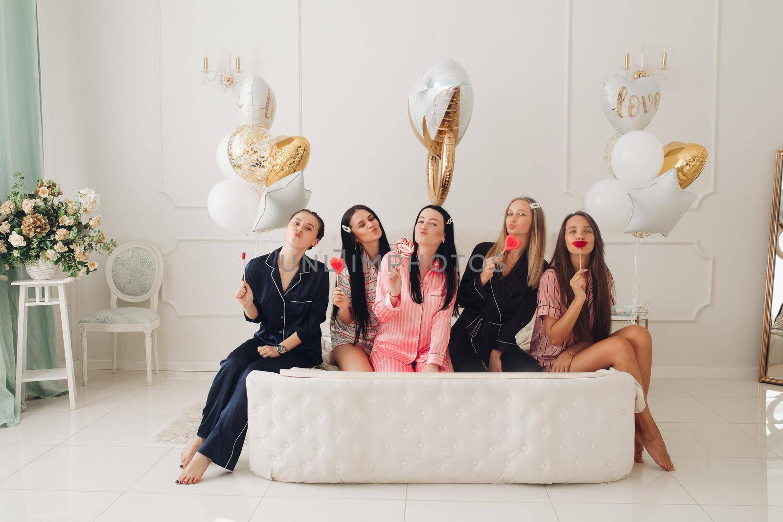 Smiling beautiful women in sleepwear spending time together during home party. Birthday party concept