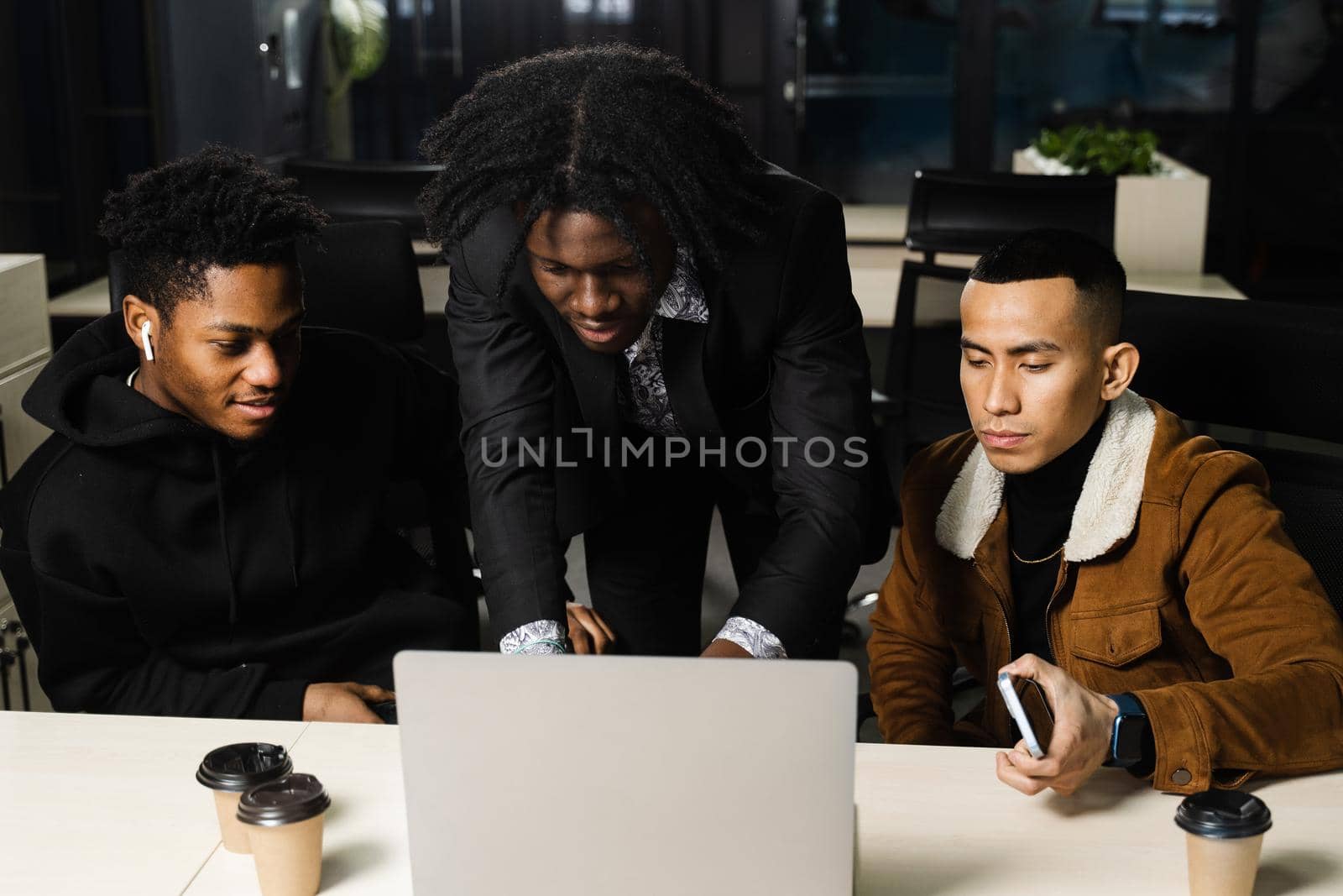 Multiethnic group teamwork of black african and asian employee working on laptop together. Discuss business process in team in office