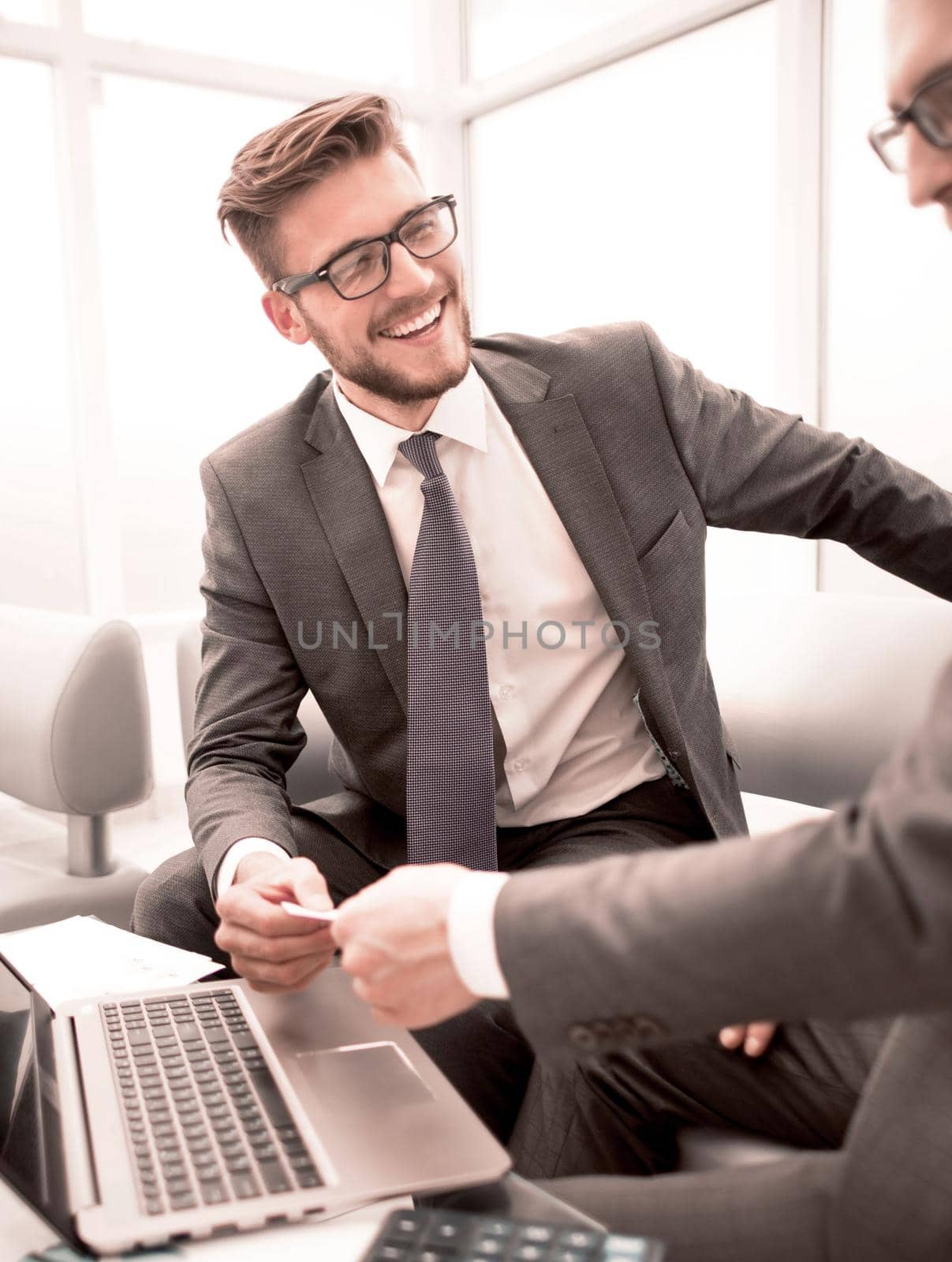 close up. smiling lawyer gives his business card to businessman.concept of partnership