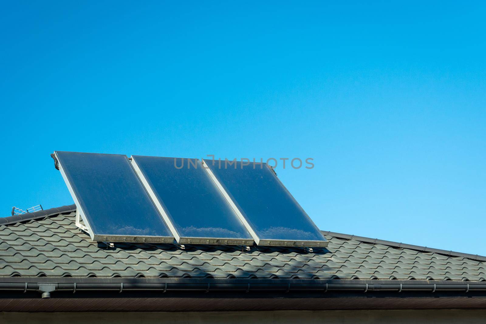 Three solar panels mounted on the roof and blue sky