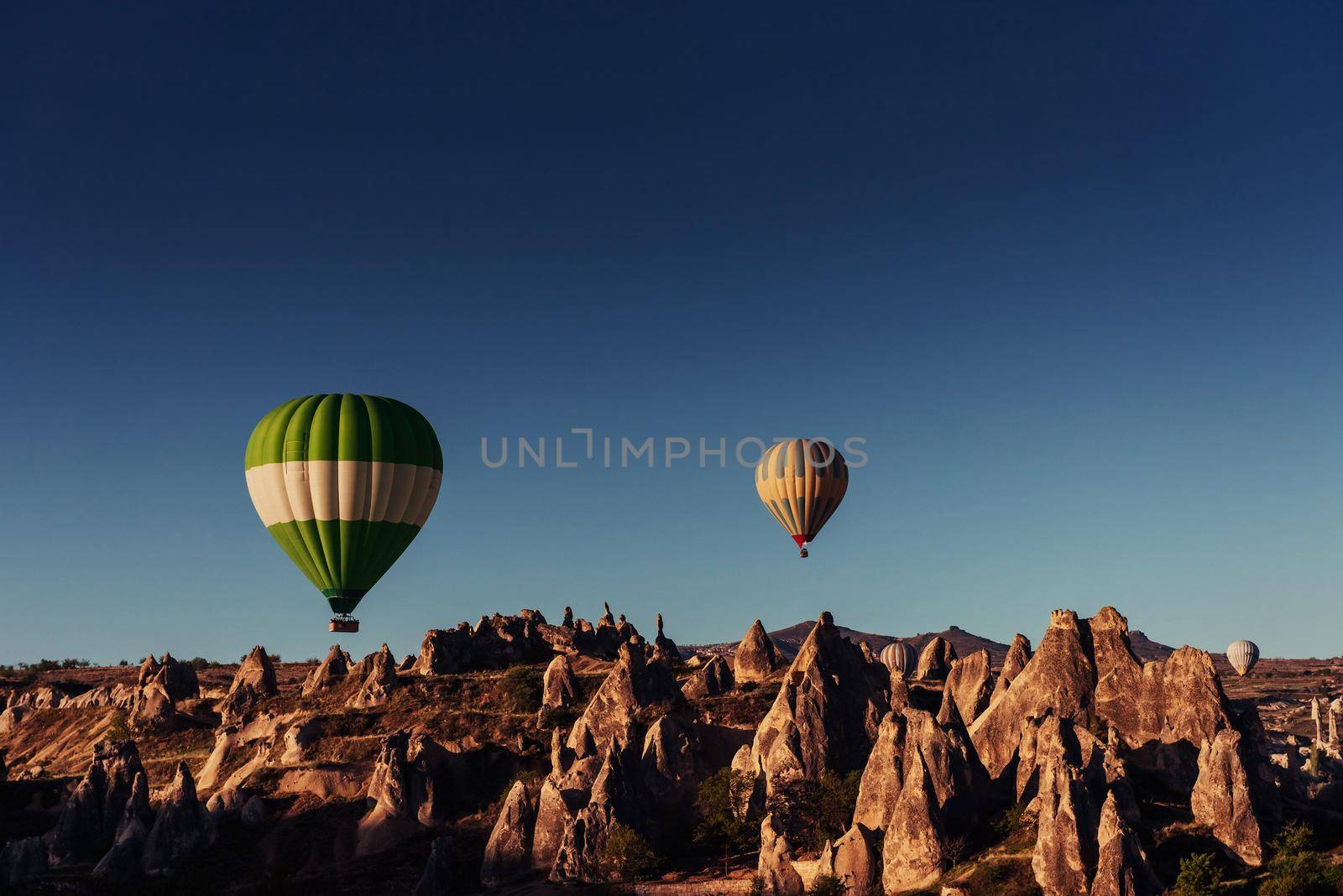 Hot air balloon flying over rock landscape at Cappadocia Turkey. Valley, ravine, hills, located between the volcanic mountains in Goreme National Park.