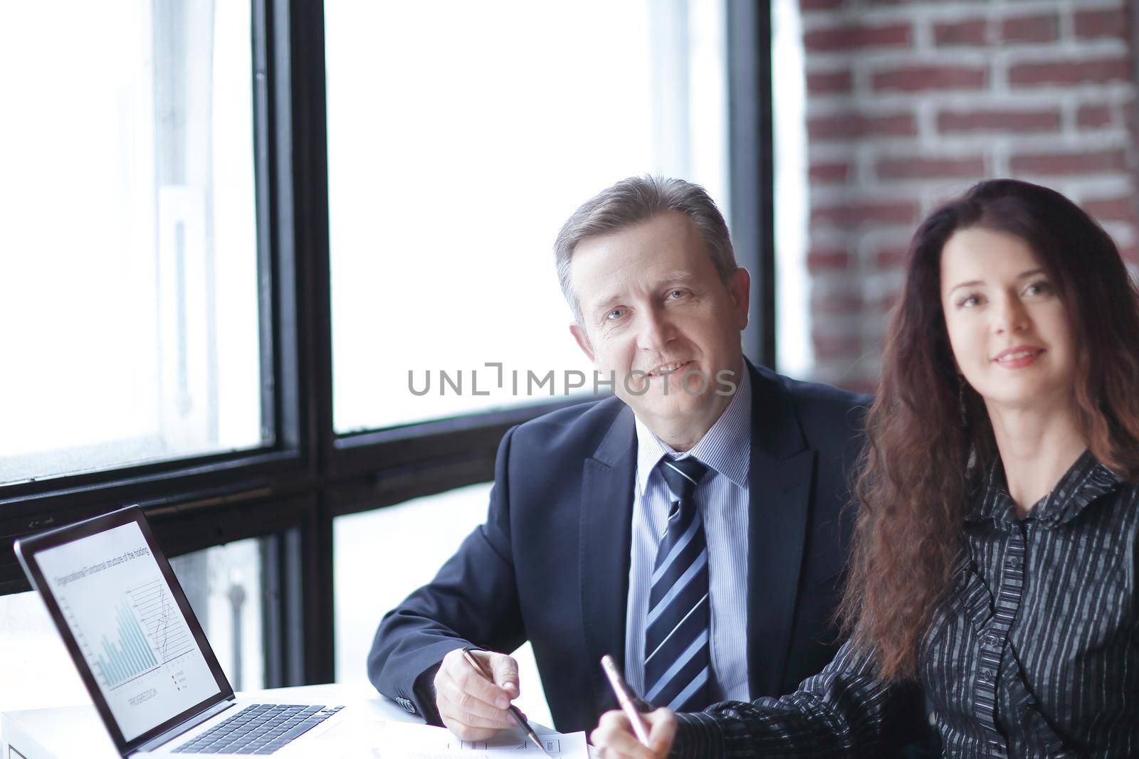 business woman and business partner sitting behind a Desk by SmartPhotoLab