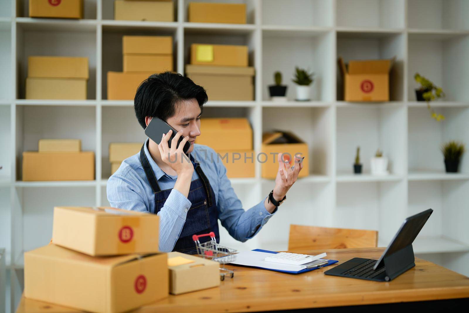 Portrait asian man are receiving orders via cell phone. Small business entrepreneur SME working with box at home, SME e-commerce digital technology concept