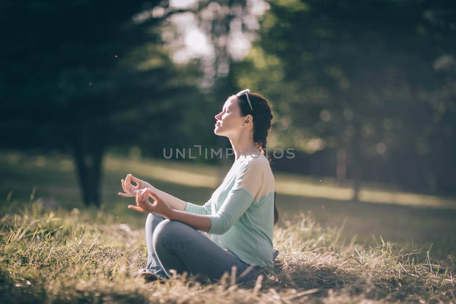 beautiful young woman meditating in Lotus position sitting on the lawn. photo with copy space