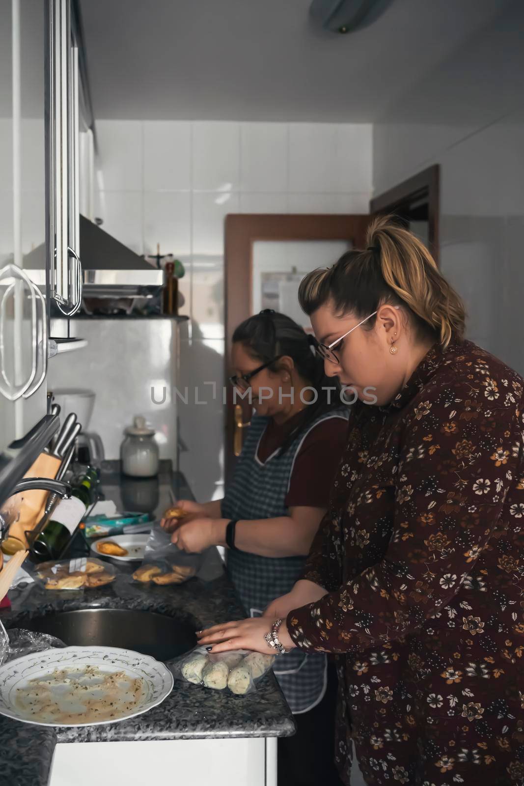 senior mother teaching her daughter how to cook by barcielaphoto