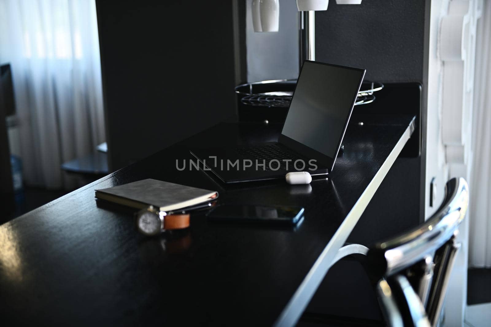 Office accessories, laptop, earphones on the box, watch, mobile phone and gray notepad on wooden table at home kitchen