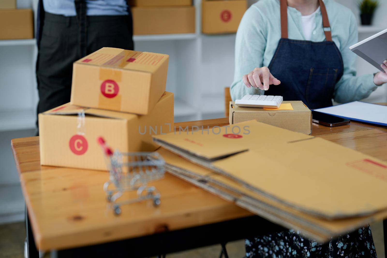 Close up startup small business owner working with tablet at workplace. freelance man and woman seller check product order, packing goods for delivery to customer. Online selling, e-commerce, shipping concept.