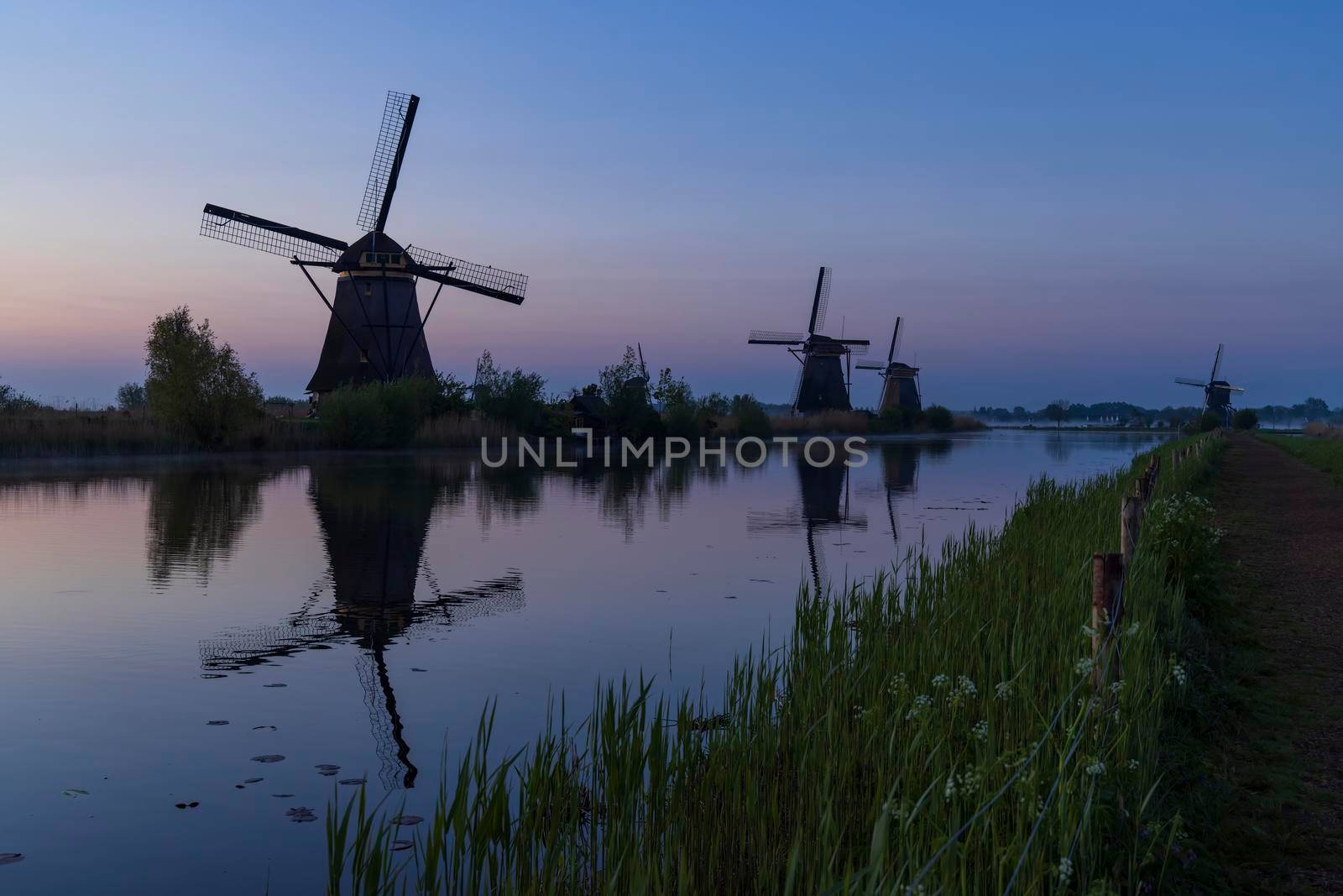Traditional Dutch windmills with a colourful sky just before sunrise in Kinderdijk, The Netherlands by phbcz