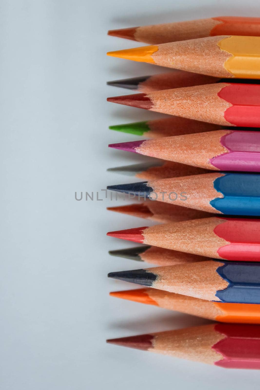multicolored wooden pencils in rainbow shades in order on a white isolated background mock up, vertical, high quality photo.