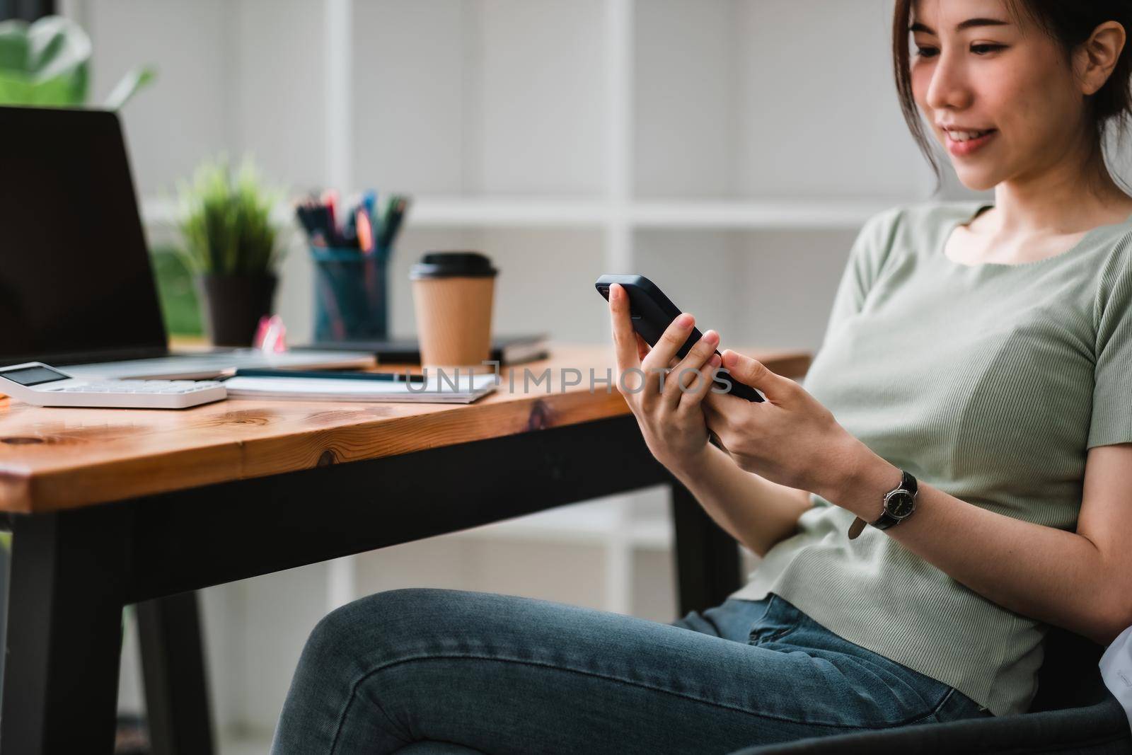 Shot of asian woman using mobile phone at her office with business accounting workplace.
