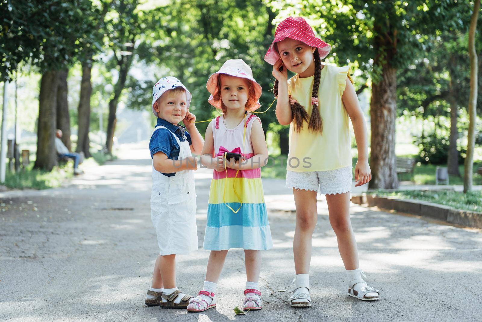 Cute girl and boy listening to music through headphones on the street.