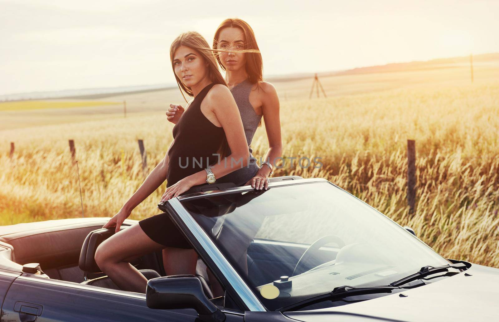 Girls posing for the camera in a black convertible.