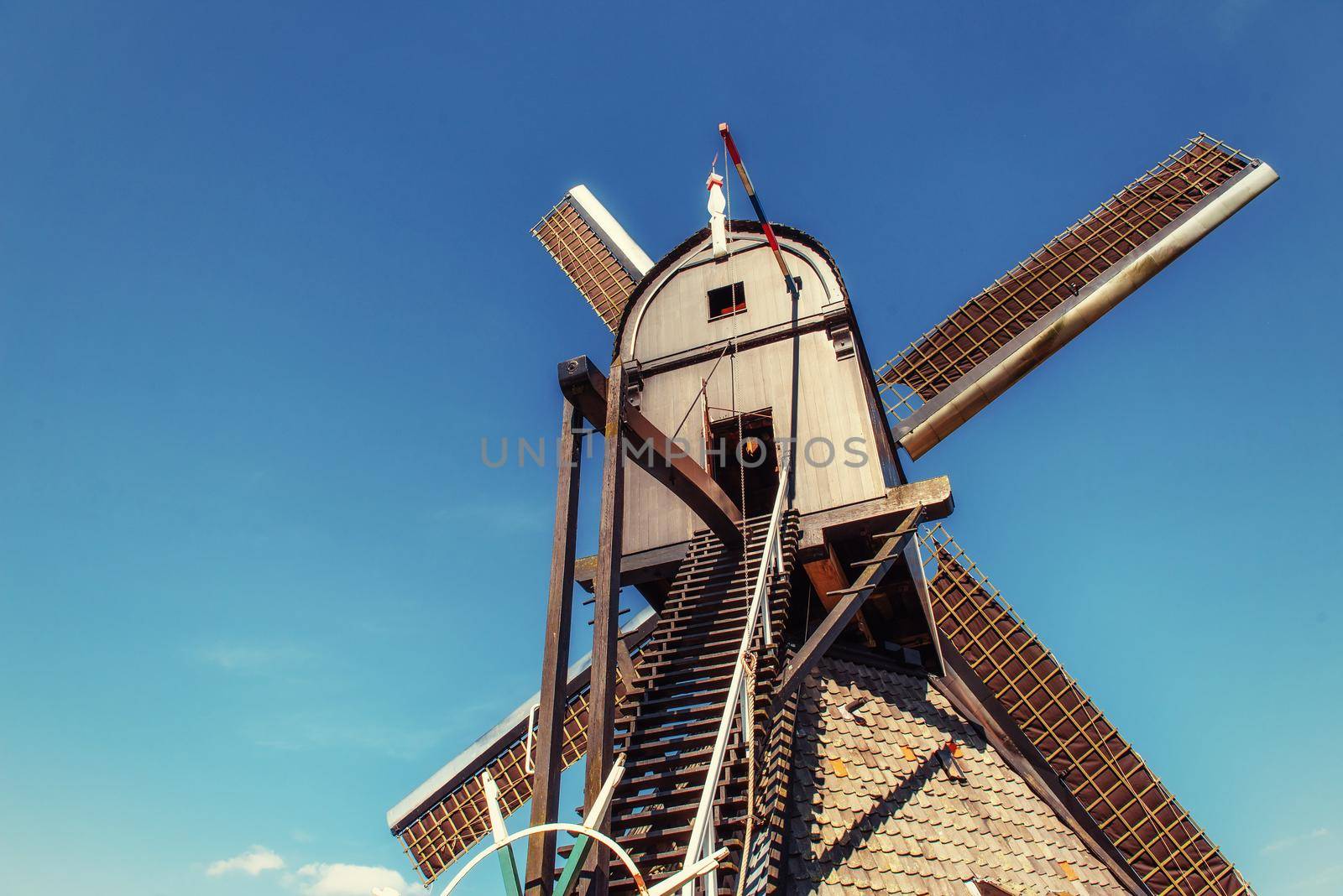 Colorful spring day with traditional Dutch windmills canal in Rotterdam. Wooden pier near the lake shore. Holland. Netherlands.