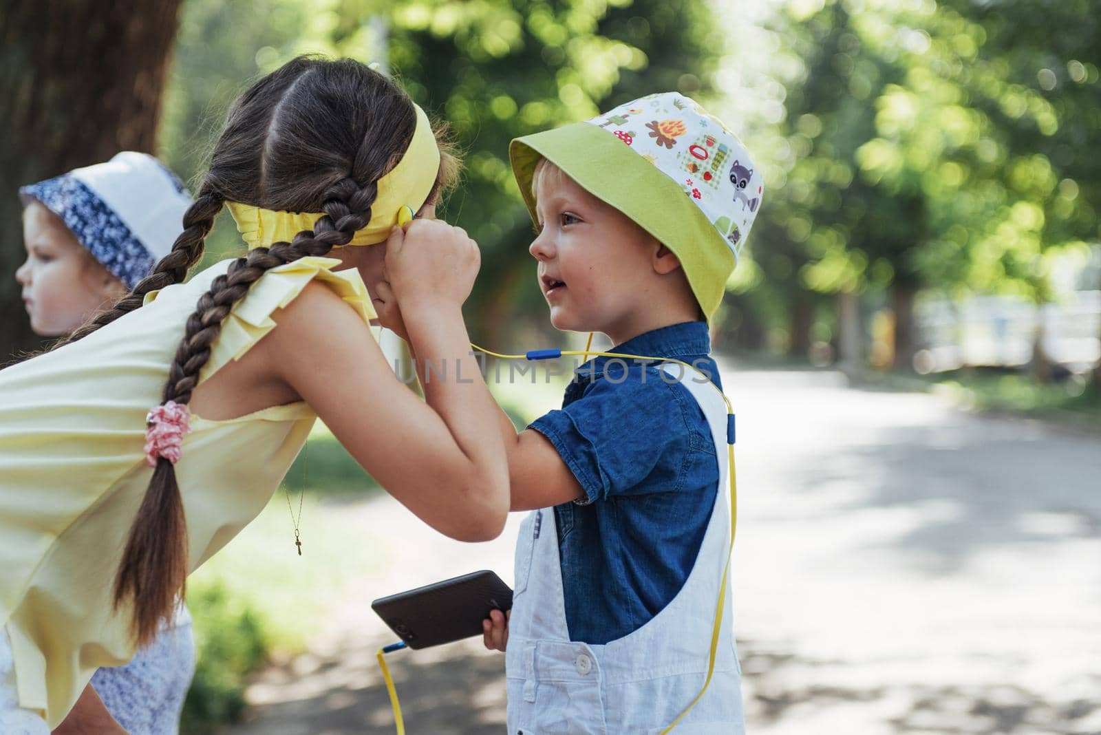 Cute girl and boy listening to music through headphones on the street.