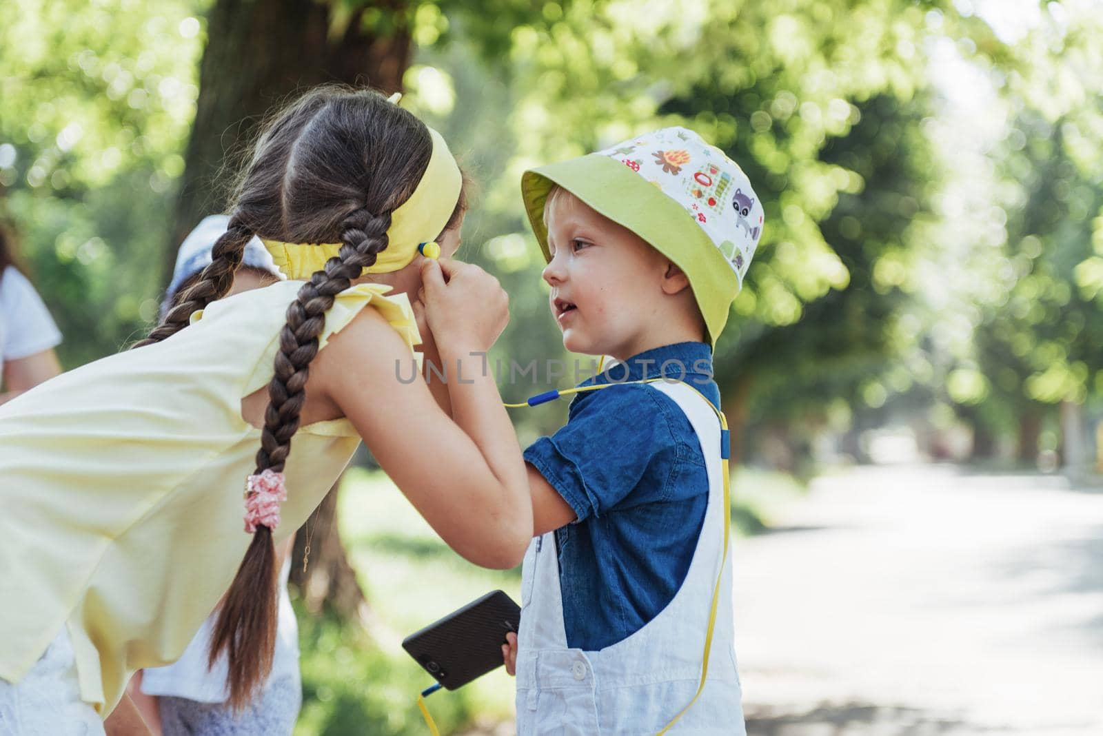 Cute girl and boy listening to music through headphones on the street.