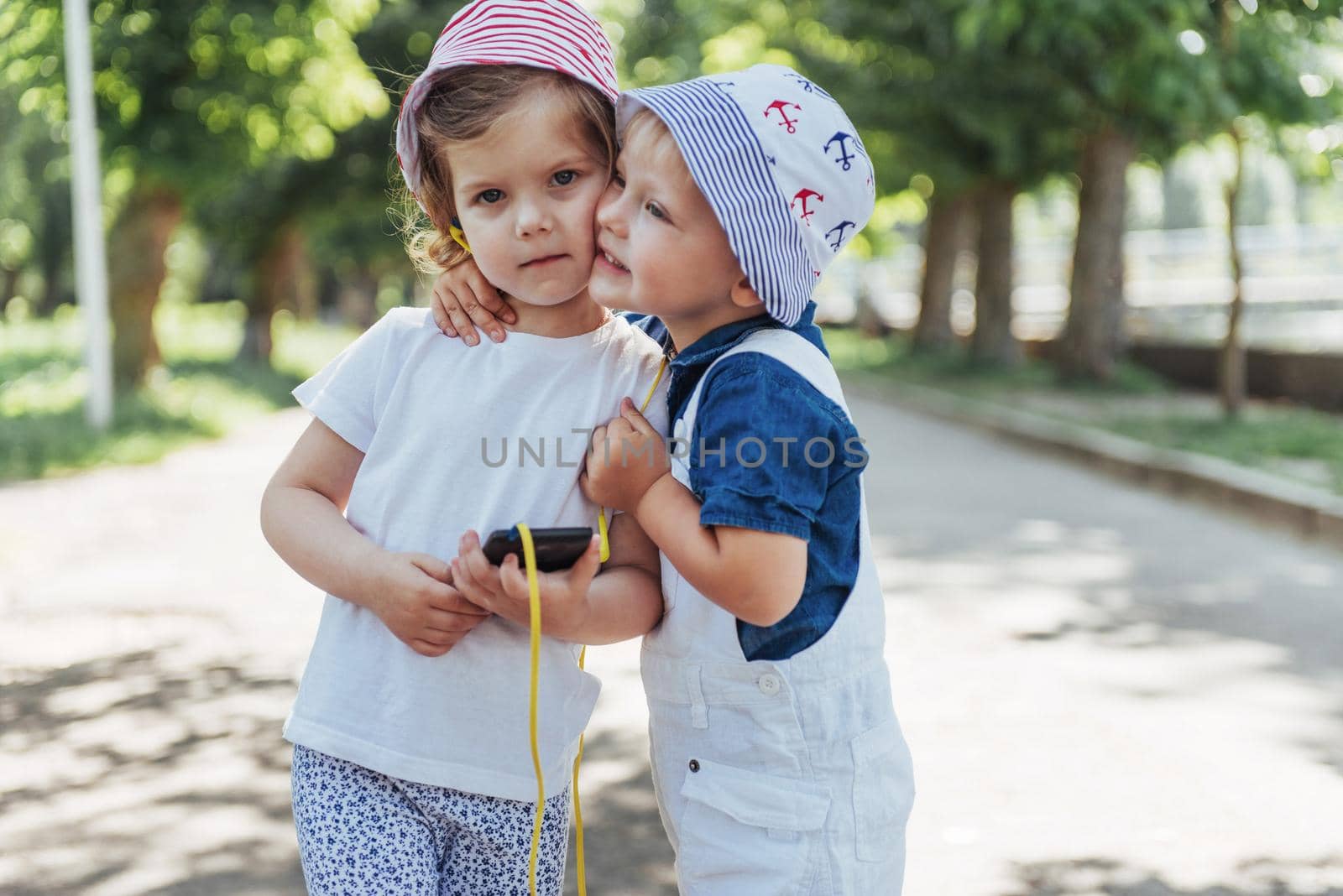 portrait of a little girl and her brother. Children playing outdoors on a sunny summer day. Family holidays.