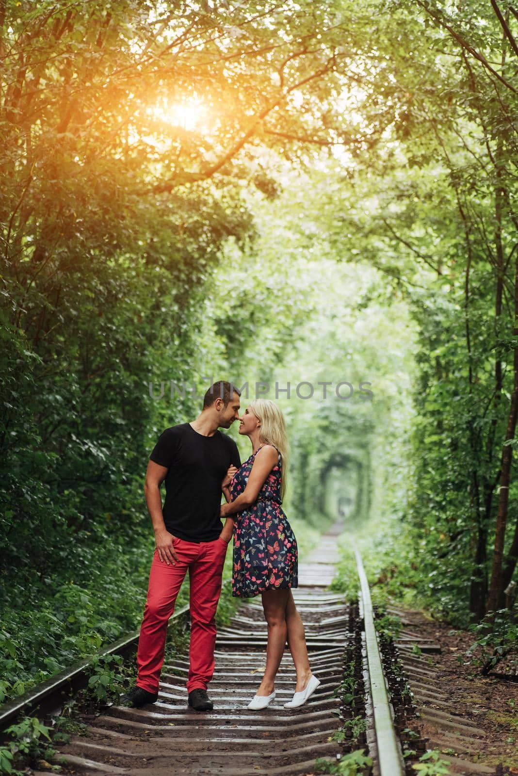 Loving couple in a tunnel of green trees on railroad by Standret