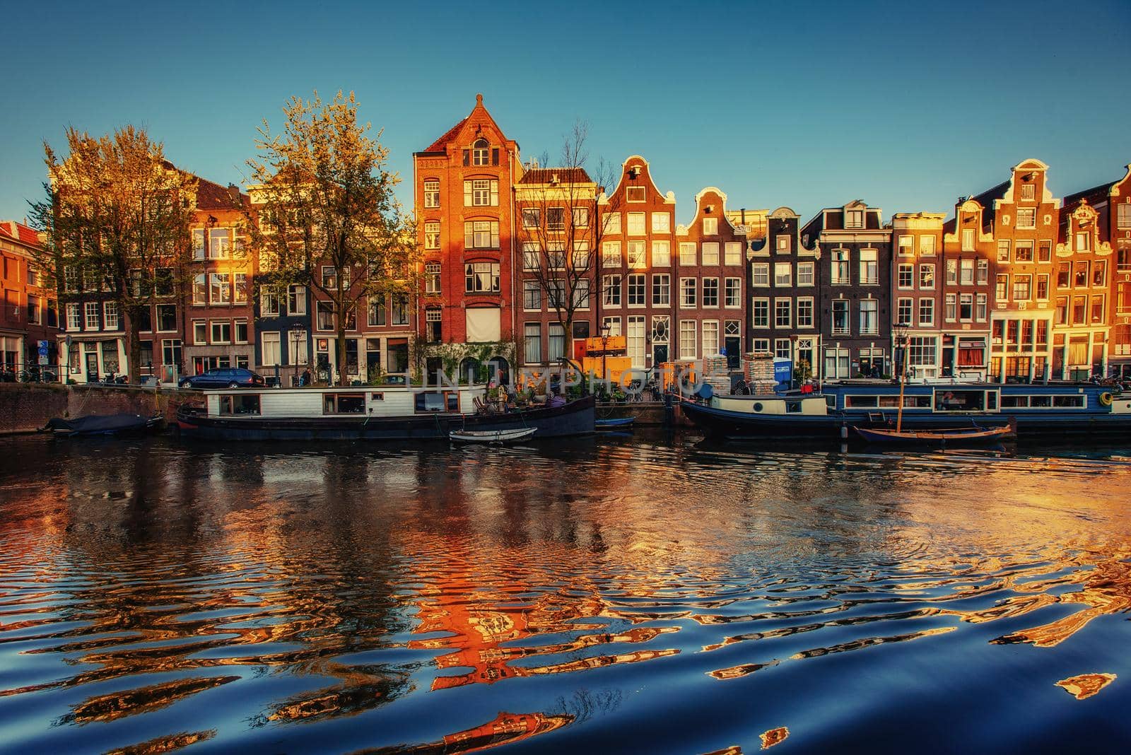 Fantastic sunset that shines on buildings and reflected in the water. Amsterdam is the capital and most populous city in Netherlands.