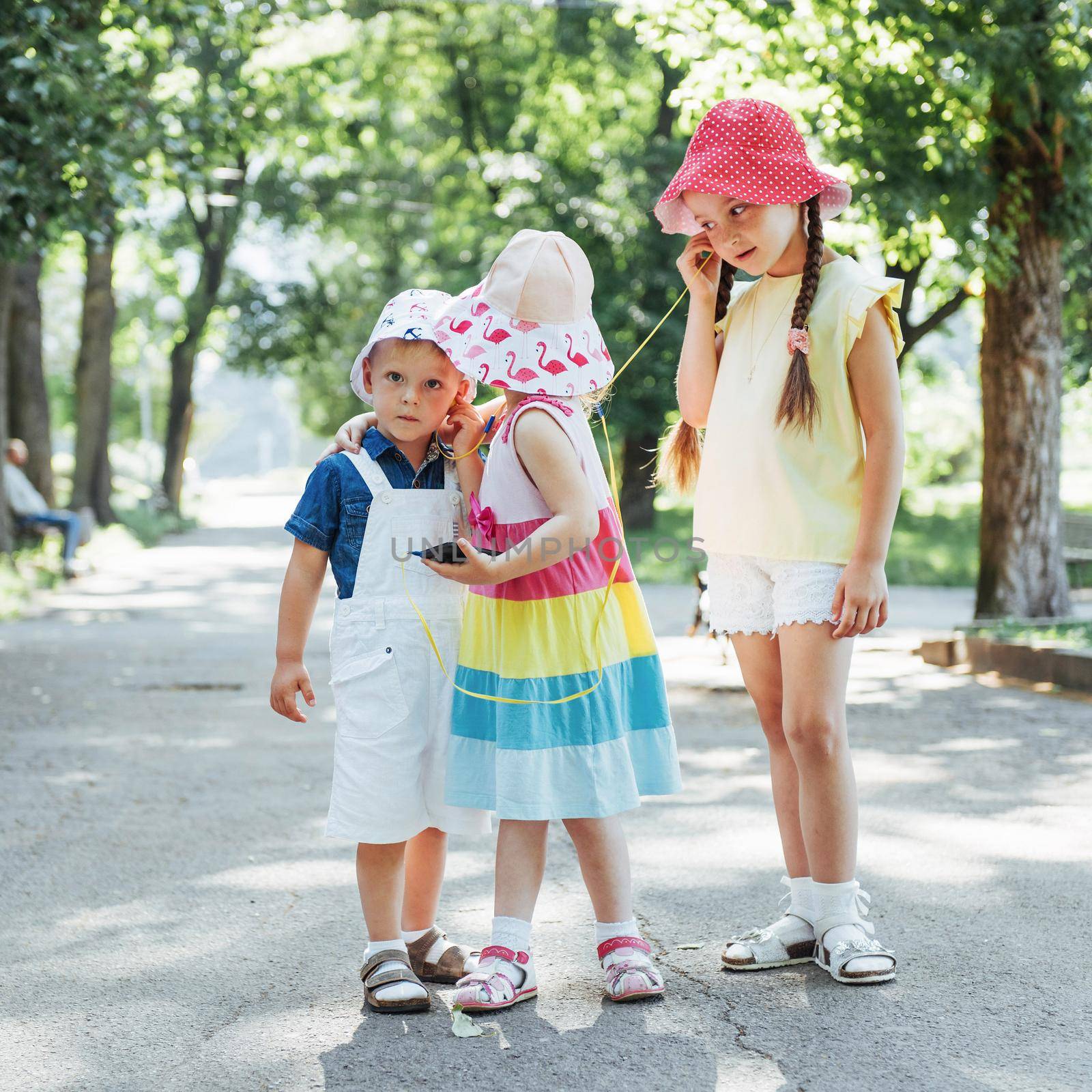 Cute girl and boy listening to music through headphones on the street.