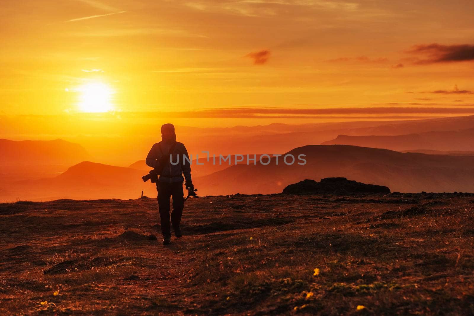Happy man standing on a cliff at sunset.
