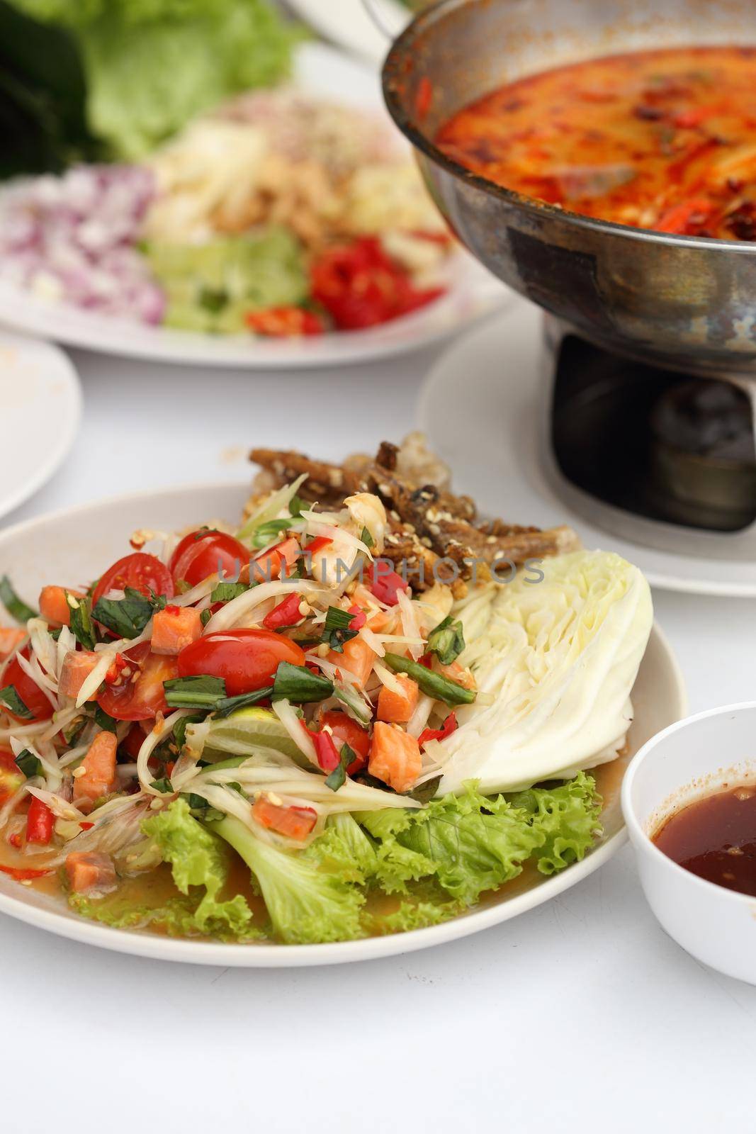 papaya spicy salad with salmon on white table in restaurant